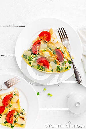 Omelet. Eggs fried. Scrambled eggs with green onion and fresh tomato. Omlette on white plate. Breakfast. Top view Stock Photo