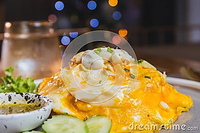 Omelet, fried beaten eggs on a white plate. Placed on a wooden table ready to eat. Stock Photo
