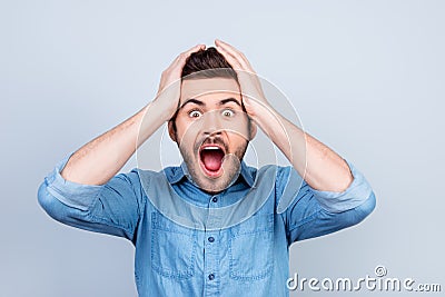 Omg! No way! Very shocked young man is holding his head with bit Stock Photo