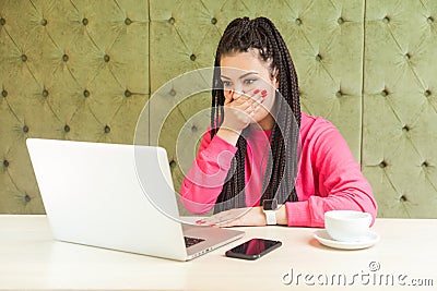 OMG! Portrait of unbelievable shocked young worker with black dreadlocks hairstyle in pink blouse are sitting in cafe, working and Stock Photo