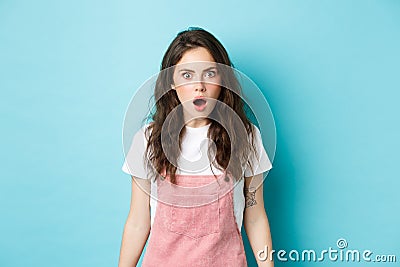 Omg what. Shocked teen girl with curly hair, drop jaw and gasping, staring with disbelief at something shocking, hear Stock Photo