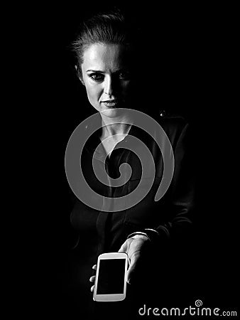 Woman in dark dress isolated on black showing smartphone Stock Photo