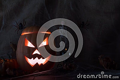 Ominous glowing jack head on background with spider web, skeleton, candle Stock Photo