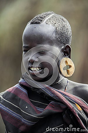 Portrait of Brave African Young Boy with a big traditional wooden earrings with the Crosses in the local Mursi tribe village Editorial Stock Photo