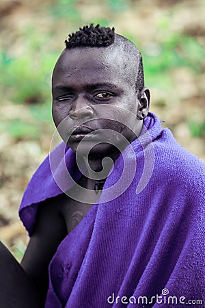Portrait of Serious and Brave African Man in Traditional dress and Wooden Stick in the local Mursi tribe village Editorial Stock Photo