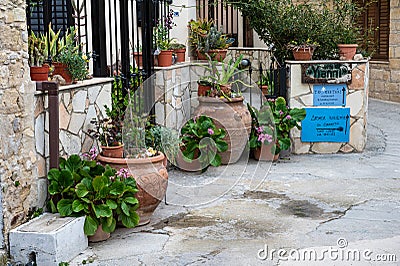 Omodos, Limassol District, Cyprus - Traditional pottery and flowers in a front garden of a narrow alley Editorial Stock Photo