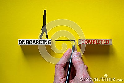 Onboarding completed symbol. Wooden blocks with words `onboarding completed`. Businessman hand. Businesswoman icon. Beautiful Stock Photo