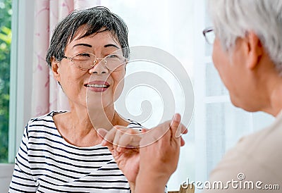 One Asian elderly woman hook each others little finger to the other with smiling in front of balcony in the house Stock Photo