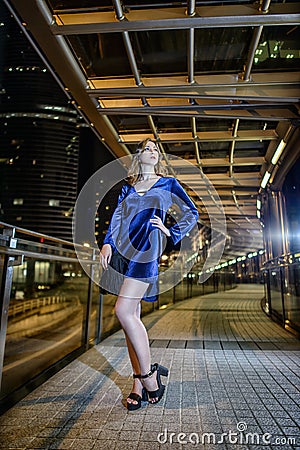 Beautiful girl brown hair, long skinny legs, fashion style blue short velvet dress, with a black little bag in Hong Kong Stock Photo