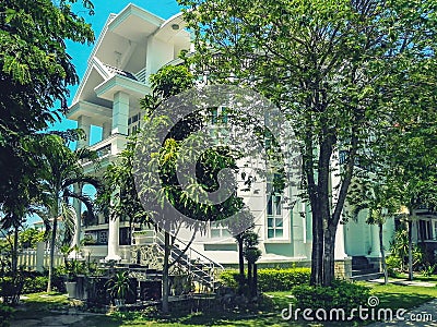 One beautiful three-story house with palm trees, trees, and landscape design in the summer. Stock Photo