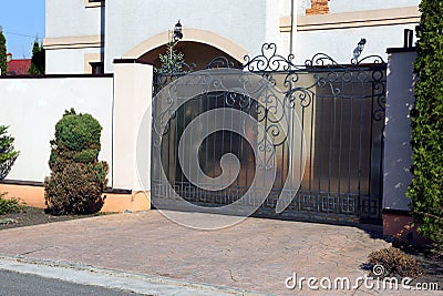 Black private metal gates with a wrought pattern on the street near the gray pavement Stock Photo