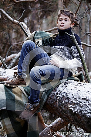 One boy in plaid walks in the snow in the autumn forest. alone i Stock Photo