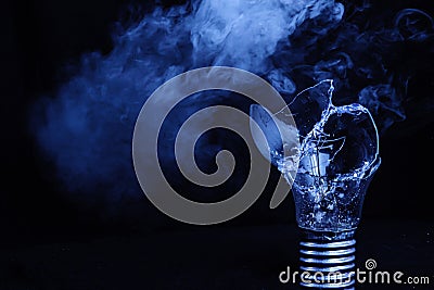 One broken light bulb on a blue background with smoke. Overdue idea concept Stock Photo