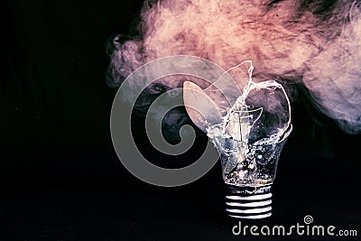 One broken light bulb on a blue background with smoke. Overdue idea concept Stock Photo