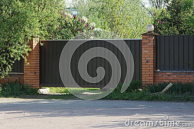 One brown gate and part of the fence of bricks Stock Photo