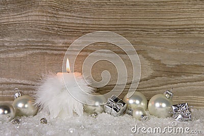 One burning candle with white feathers and snow and silver decor Stock Photo
