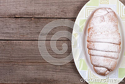 One croissant sprinkled with powdered sugar on old wooden background with copy space for your text. Top view Stock Photo