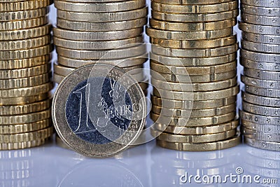 A one euro coin in front of many more coins stacked in columns o Stock Photo