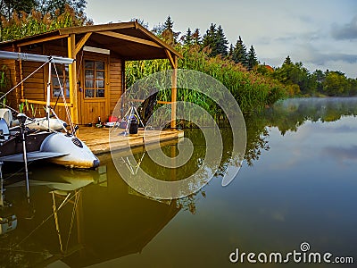 One Fisherman house and inflatable boat on river hiding in a reeds Stock Photo