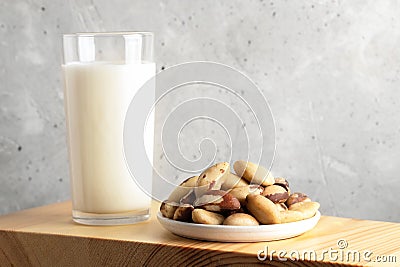 One glass of vegan milk made of brazil nut and nuts in plate on wooden board. Close up. Copy space. Stock Photo