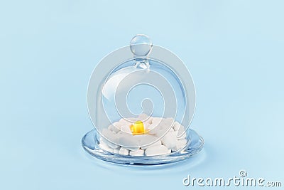 One golden and many white tablets in glass dome container Stock Photo