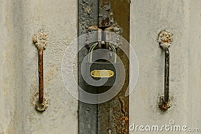 Gray padlock hangs on a closed iron door Stock Photo