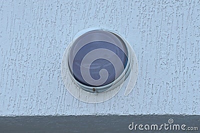 One gray round glass lantern on a white concrete wall of a building Stock Photo