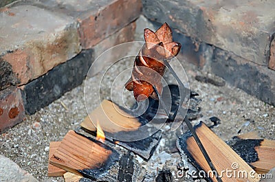 One grilling sausage over a fire in summer Stock Photo