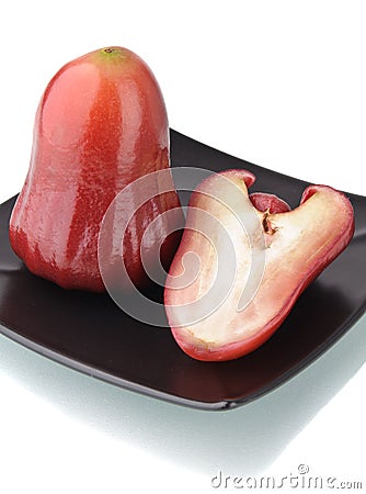 One and a half of red rose apple on black plate Stock Photo