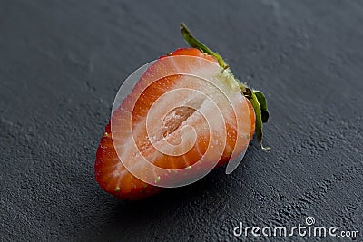 One half of strawberry, cut red beautiful strawberry close-up, on a black dark concrete background. Macro shooting. Fruit erotica Stock Photo