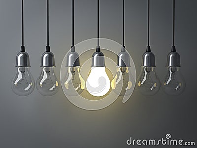 One hanging light bulb glowing different and standing out from unlit incandescent bulbs Stock Photo