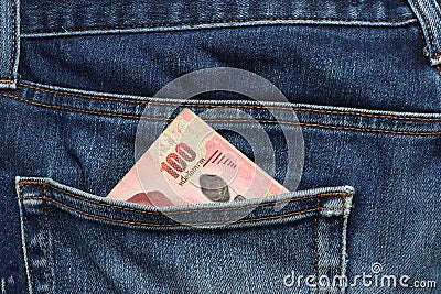 One hundred baht banknote of Thailand in the back pocket of jeans Stock Photo