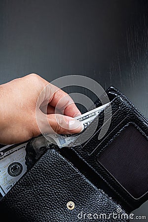 One hundred dollar bill in black wallet in hand Stock Photo