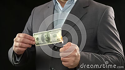 One hundred dollar bill on fire, male going bankrupt, losing money, inflation Stock Photo