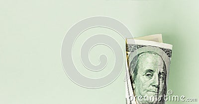 One hundred dollar bill roll with the face of Benjamin Franklin on a green background Stock Photo