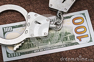 One hundred dollars and handcuffs on the table. Concept of illegal foreign exchange transactions Stock Photo