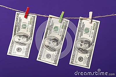 One hundred dollars hanging on clothesline with wooden clips on blue background Stock Photo