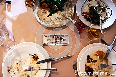 One hundred dollars lie among the dirty dishes, tips Stock Photo