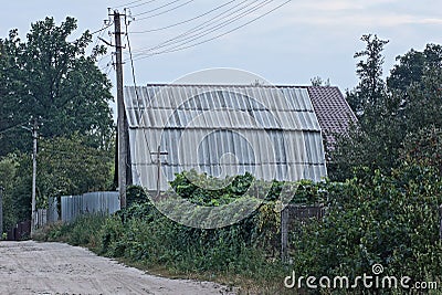 One large attic of a rural house under a gray slate roof behind a fence Stock Photo