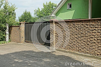 One large black metal gate and part of a brown wall Stock Photo