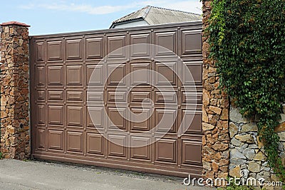 One large brown gate and part of a stone fence Stock Photo