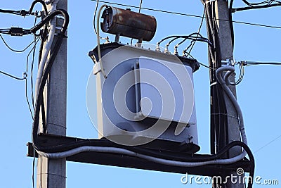 One large iron transformer with electrical wires on two gray concrete pillars Stock Photo