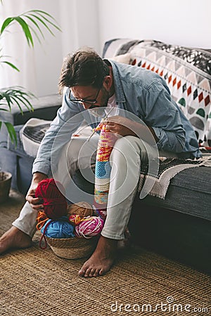 One man at home doing knit activity alone sitting on the sofa. Mature male people love knitting work for no stress hobby and relax Stock Photo