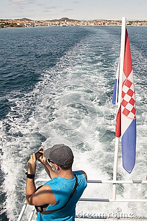 One man standing on a back of a ship taking photo on mobile phone and Croatian flag Editorial Stock Photo