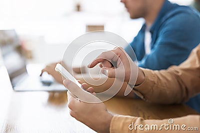 One man types in his laptop and another points with his finger in smarphone, people and digital technologies concept Stock Photo