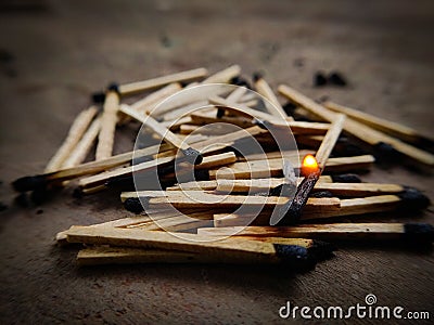 One Matchstick burning on top of many exhausted matchsticks Stock Photo