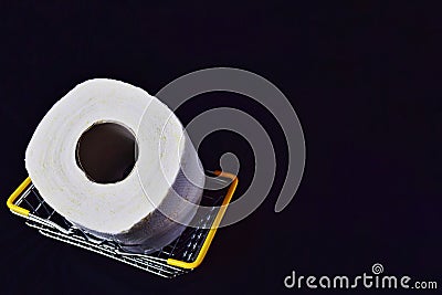 one metal food basket containing one roll of toilet paper. basket with yellow handles on a black background. Stock Photo