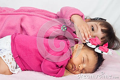 One month old baby girl at home with her big sister. Love between siblings concept. Family concept Stock Photo