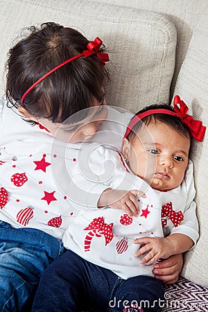 One month old baby girl at home with her big sister. Love between siblings concept. Family concept Stock Photo