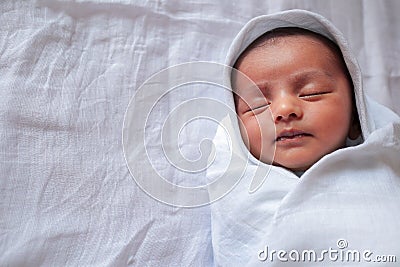 A one month old baby sleeping and swaddled in white cloth lying in white cloth background Stock Photo